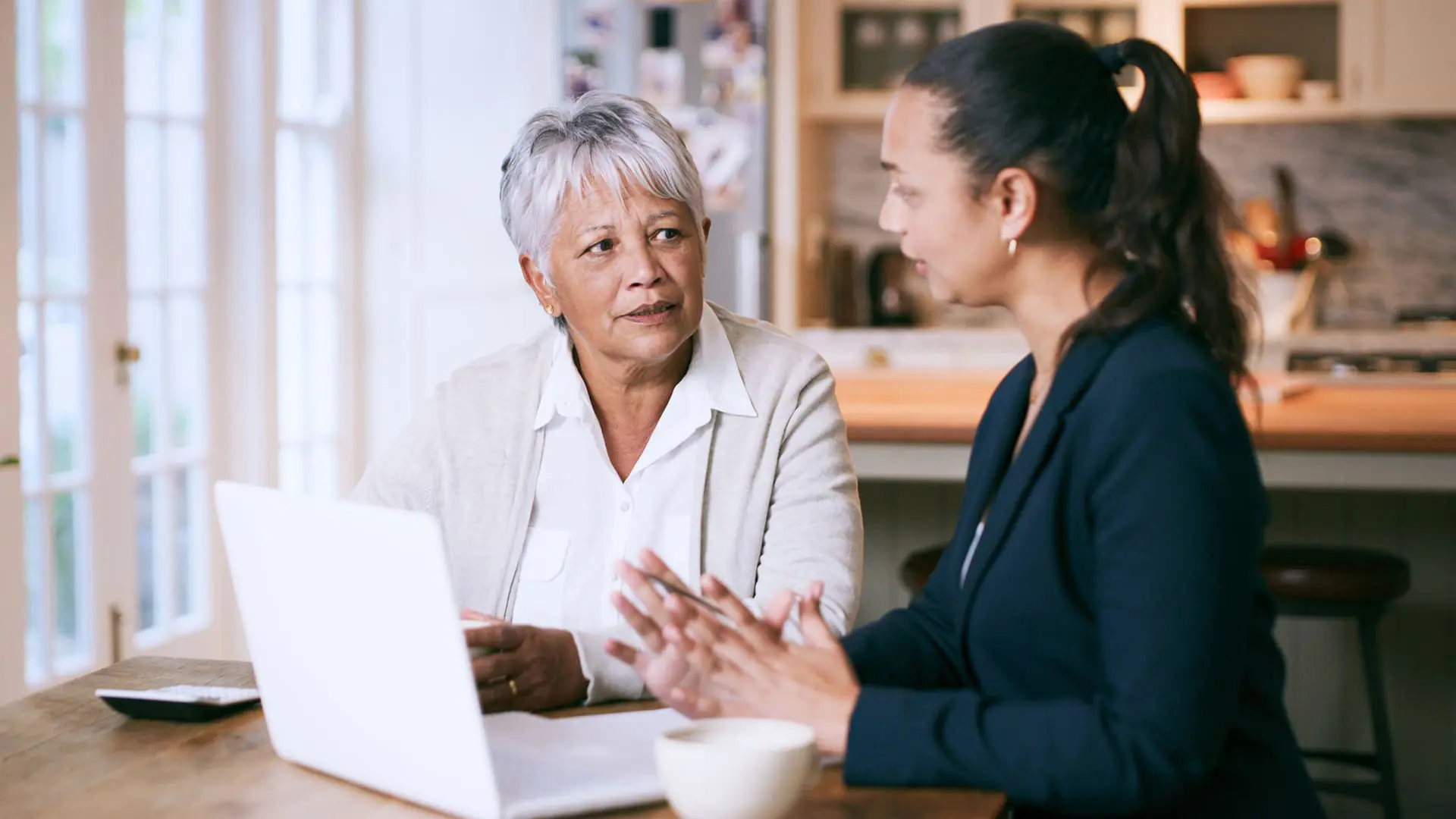 Shot of a senior woman using a laptop during a meeting with a consultant at home Shot of a senior woman using a laptop during a meeting with a consultant at home