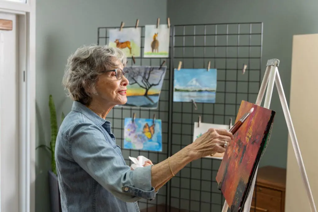 Older adult woman painting in art studio to practice mindfulness activities for seniors at Canterbury Woods Williamsville.