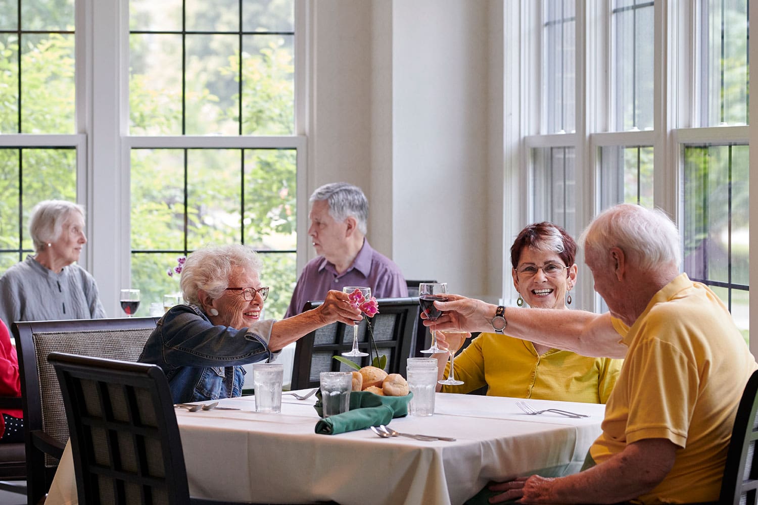 Seniors toasting with wine glasses in the Dining Room at Canterbury Woods