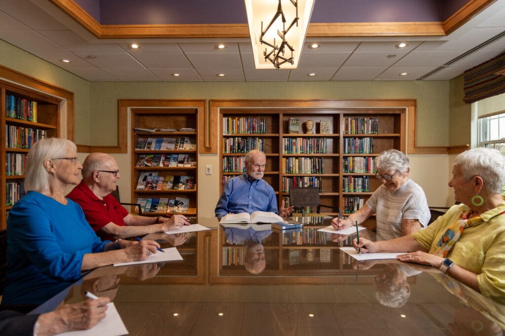 A group of older adults journaling in library to practice mindfulness activities for seniors at Canterbury Woods Williamsville.